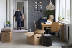 Ett rum med flyttlådor och en kvinna packar upp efter flytt